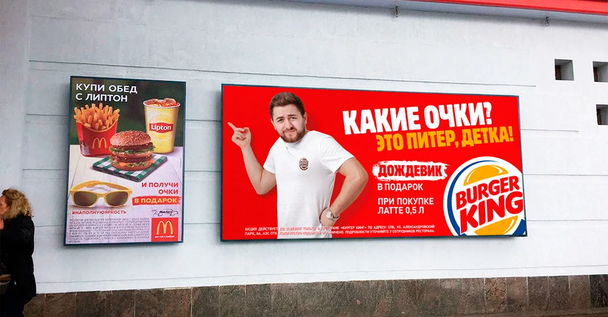 Вместо солнечных очков, которые предлагает McDonalds в дождливом Санкт-Петербурге, Burger King дарит клиентам дождевик.