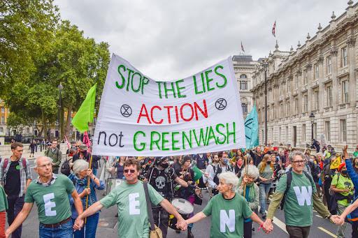 Протестующие несут транспарант с надписью «Остановите ложь — действуйте, а не занимайтесь гринвошингом» во время демонстрации на Даунинг-стрит в Лондоне.